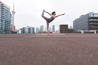 Woman doing yoga on rooftop with city skyline