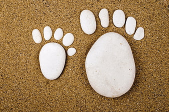 White stones arranged as footprints on sand background