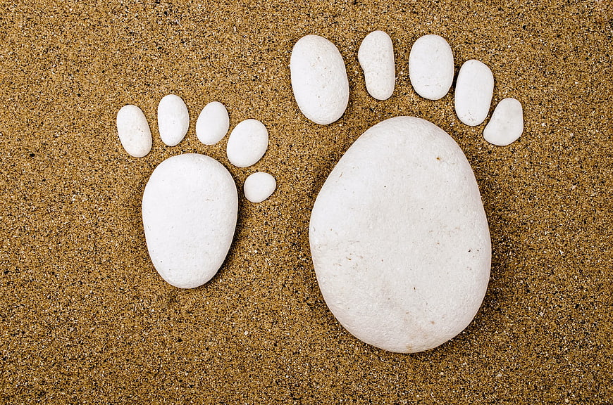 White stones arranged as footprints on sand background