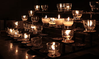 Rows of lit prayer candles in a dark church interior