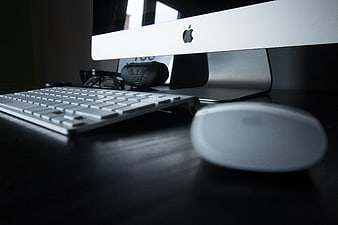 Low angle view of Apple iMac computer setup on dark desk