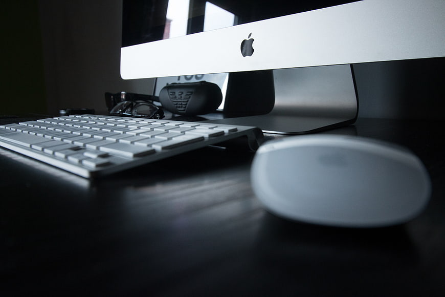 Low angle view of Apple iMac computer setup on dark desk
