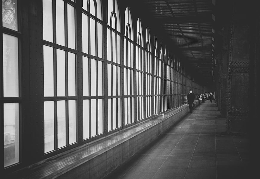 Black and white photo of a long industrial corridor with arched windows