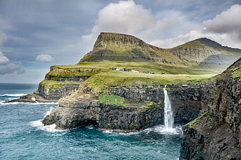 Dramatic coastal landscape with waterfall cascading into ocean