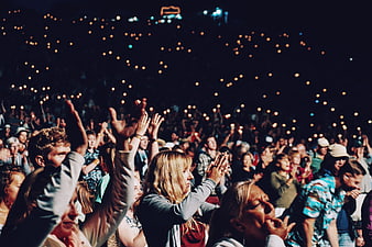 Excited concert crowd clapping with phone lights at night