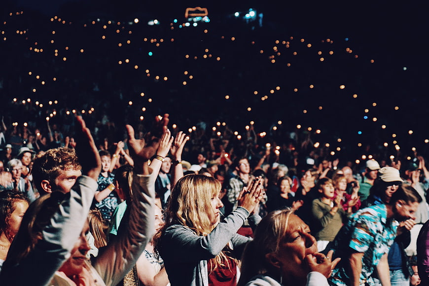 Excited concert crowd clapping with phone lights at night