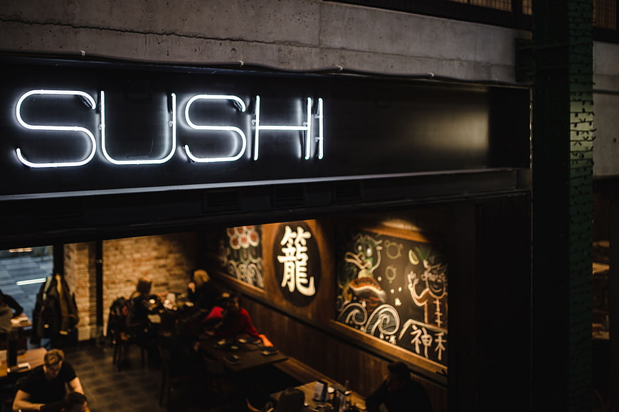 Neon Sushi Sign Above Restaurant Interior at Night