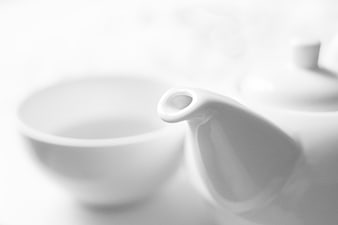 Close-up of white porcelain teapot spout and cup