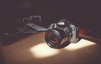 Canon DSLR Camera on Wooden Desk in Sunlight
