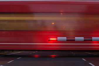 Motion blur of red train passing railway crossing barrier