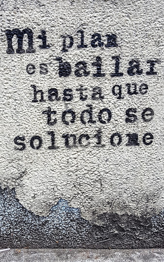 Spanish street art quote on textured concrete wall