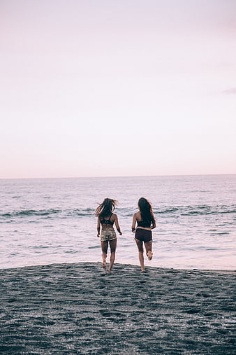 Two Women Running on Beach at Sunset