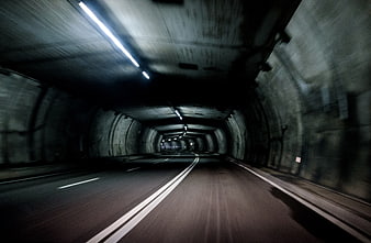 Motion blur view driving through a dark concrete tunnel at night