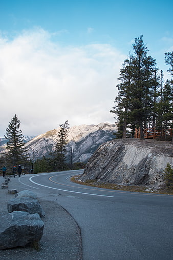 Winding Mountain Road with Snow-Capped Peaks and Hikers