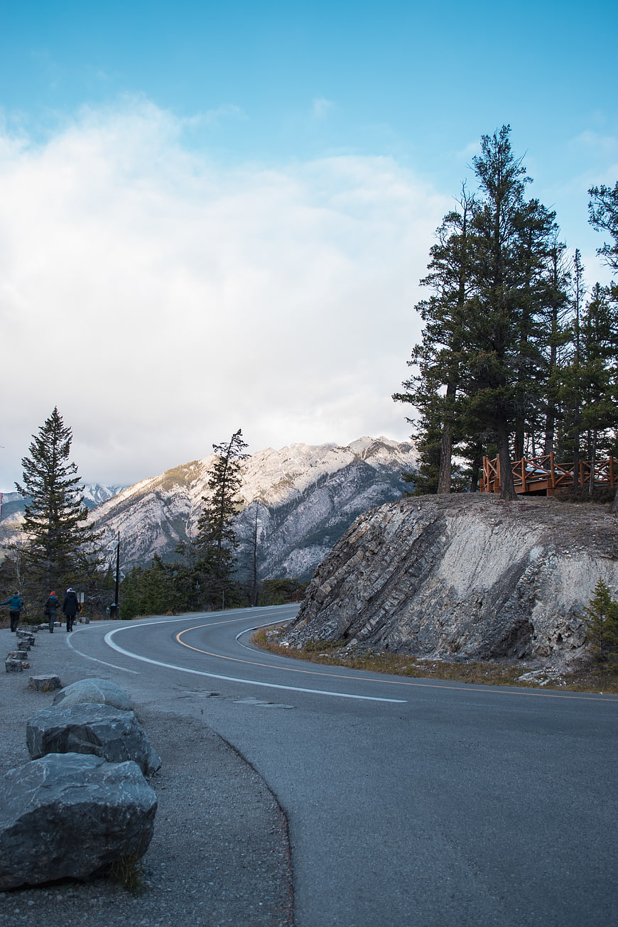 Winding Mountain Road with Snow-Capped Peaks and Hikers