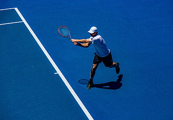 High Angle Tennis Player Serving on Blue Court