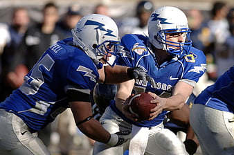 American Football Quarterback in Blue Jersey Holding Ball