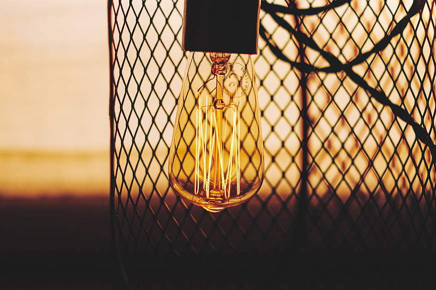 Vintage Edison Bulb Hanging in Metal Mesh Cage at Sunset