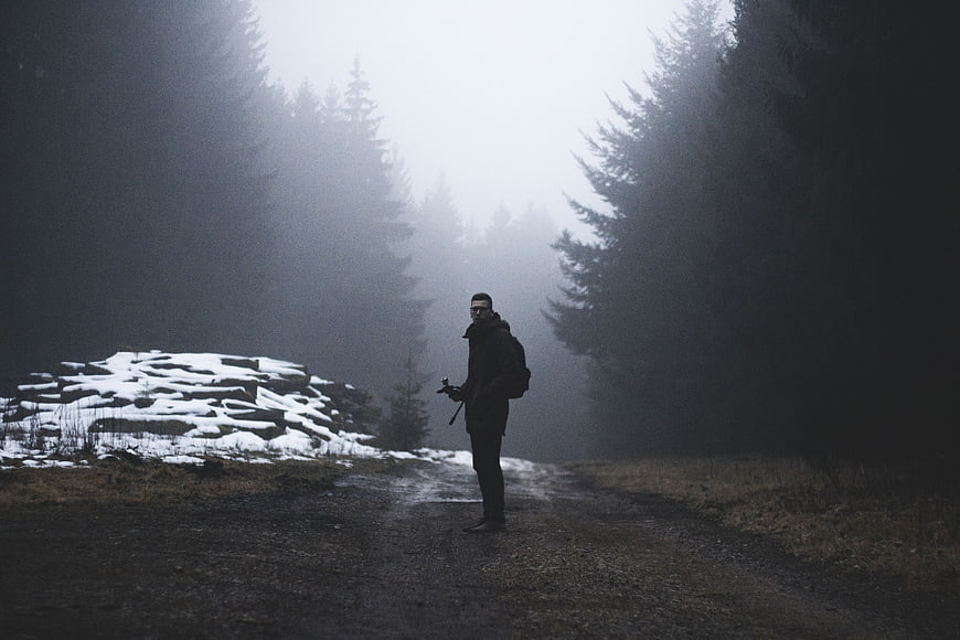 Lone Hiker Standing in Foggy Forest Path