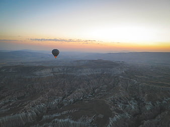 Hot Air Balloon Flying Over Cappadocia Landscape at Sunset