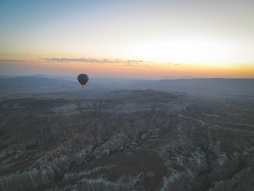 Hot Air Balloon Flying Over Cappadocia Landscape at Sunset
