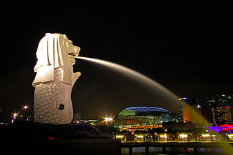Merlion statue in Singapore at night with illuminated city skyline