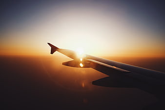 Airplane Wing Silhouette Against Golden Sunset Sky