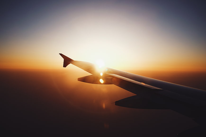 Airplane Wing Silhouette Against Golden Sunset Sky