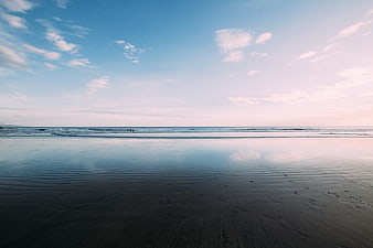 Serene Beach Landscape with Wet Sand Reflections and Blue Sky