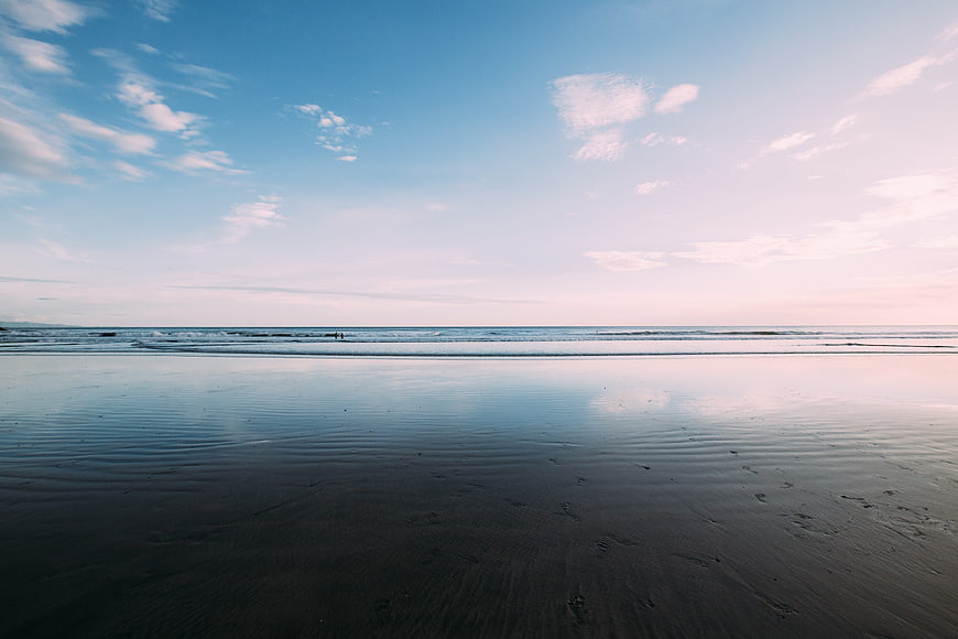 Serene Beach Landscape with Wet Sand Reflections and Blue Sky