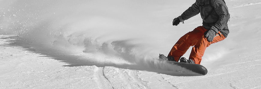 Snowboarder Carving Through Powder Snow With Orange Pants