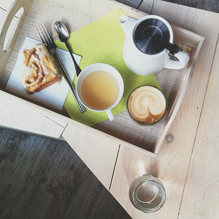 Top view of coffee, tea, and cinnamon roll on wooden tray