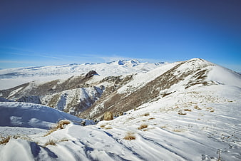 Snowy mountain ridge landscape with blue sky and distant peaks