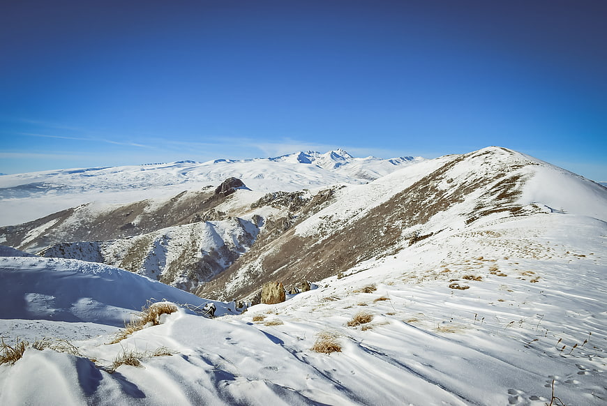 Snowy mountain ridge landscape with blue sky and distant peaks