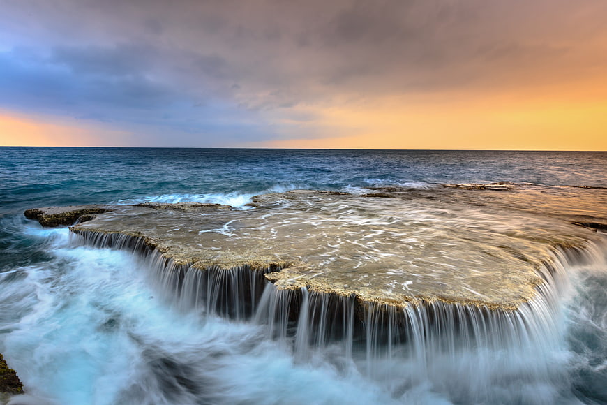 Dramatic Ocean Waterfall at Sunset with Long Exposure Flow