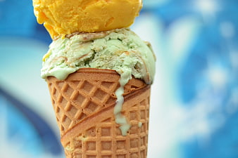 Close-up of melting mint and mango ice cream cone