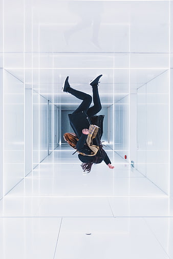 Woman jumping upside down in futuristic white corridor