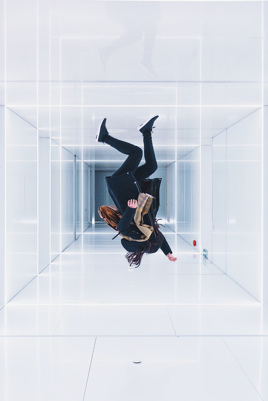 Woman jumping upside down in futuristic white corridor