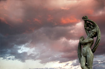 Bronze Angel Statue Against Dramatic Sunset Sky