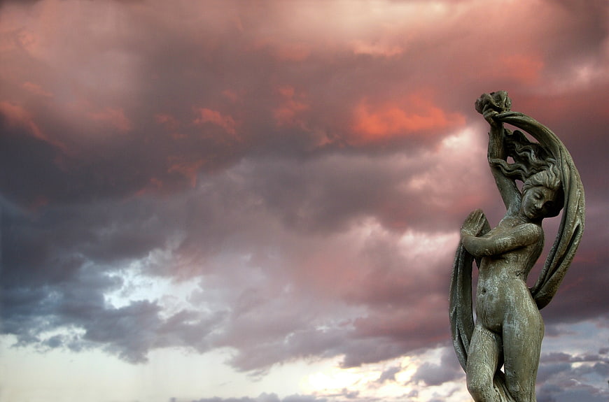 Bronze Angel Statue Against Dramatic Sunset Sky