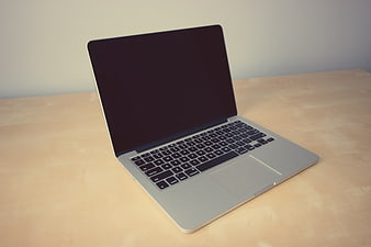 Silver laptop on wooden desk with black screen