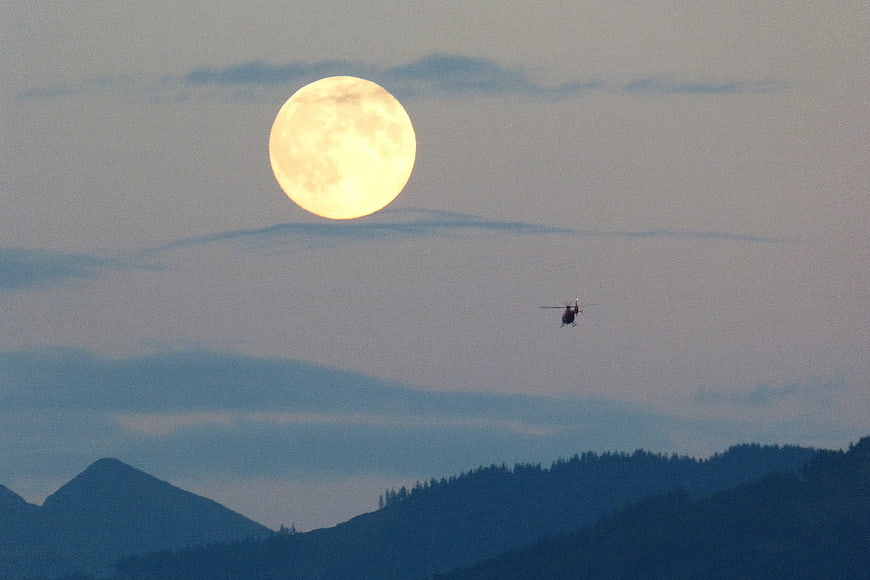 Full Moon and Helicopter Silhouette Over Mountain Ranges at Dusk