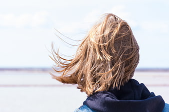 Back view of woman with windblown hair looking at horizon