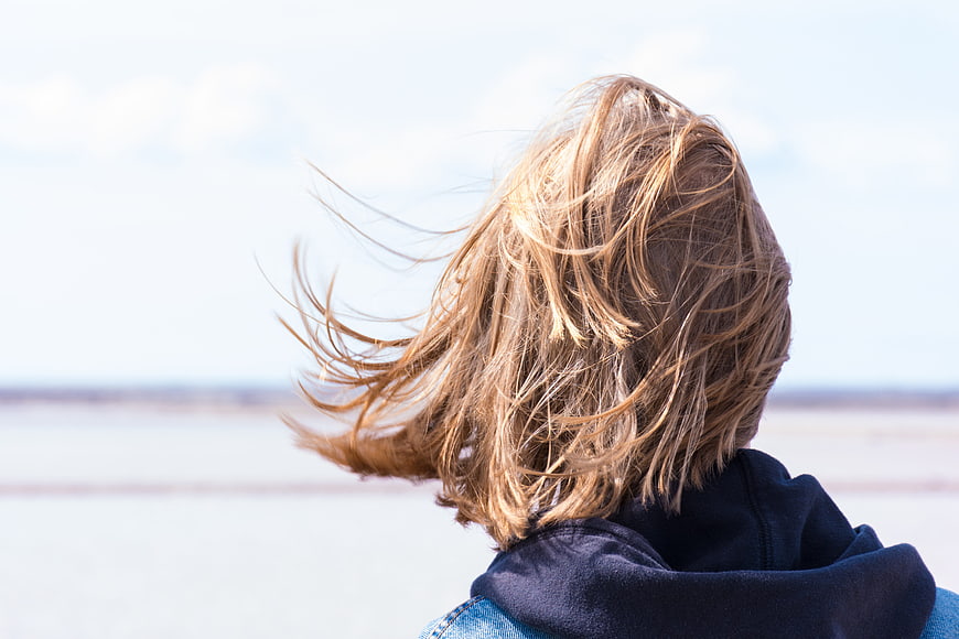 Back view of woman with windblown hair looking at horizon