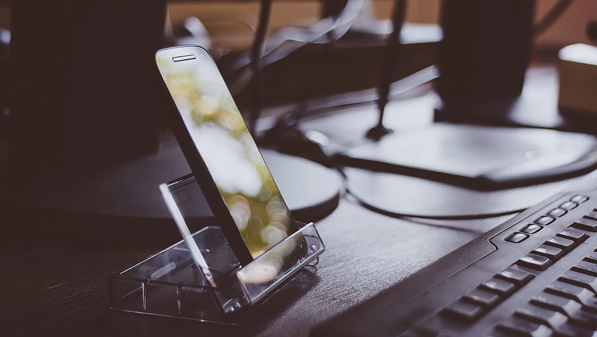 Smartphone on Clear Stand Beside Keyboard