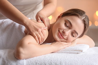 Relaxed woman receiving shoulder massage at spa