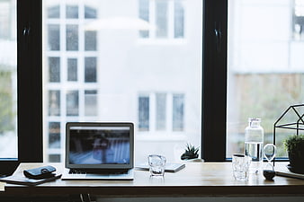 Modern workspace with laptop and water by window