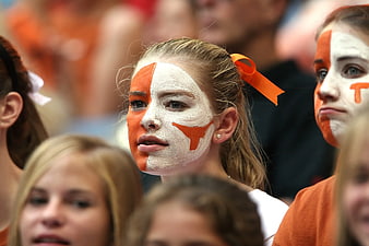 Young female fan with orange and white face paint at sports event