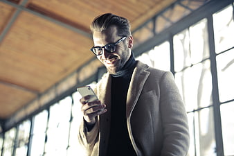 Smiling man with glasses using smartphone in modern office