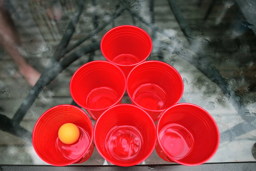 Red plastic cups arranged for beer pong with ping pong ball